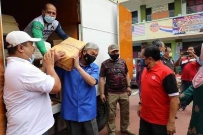 Too ill with his bad neck to attend court but UMNO boss Zahid poses lugging aid to victims